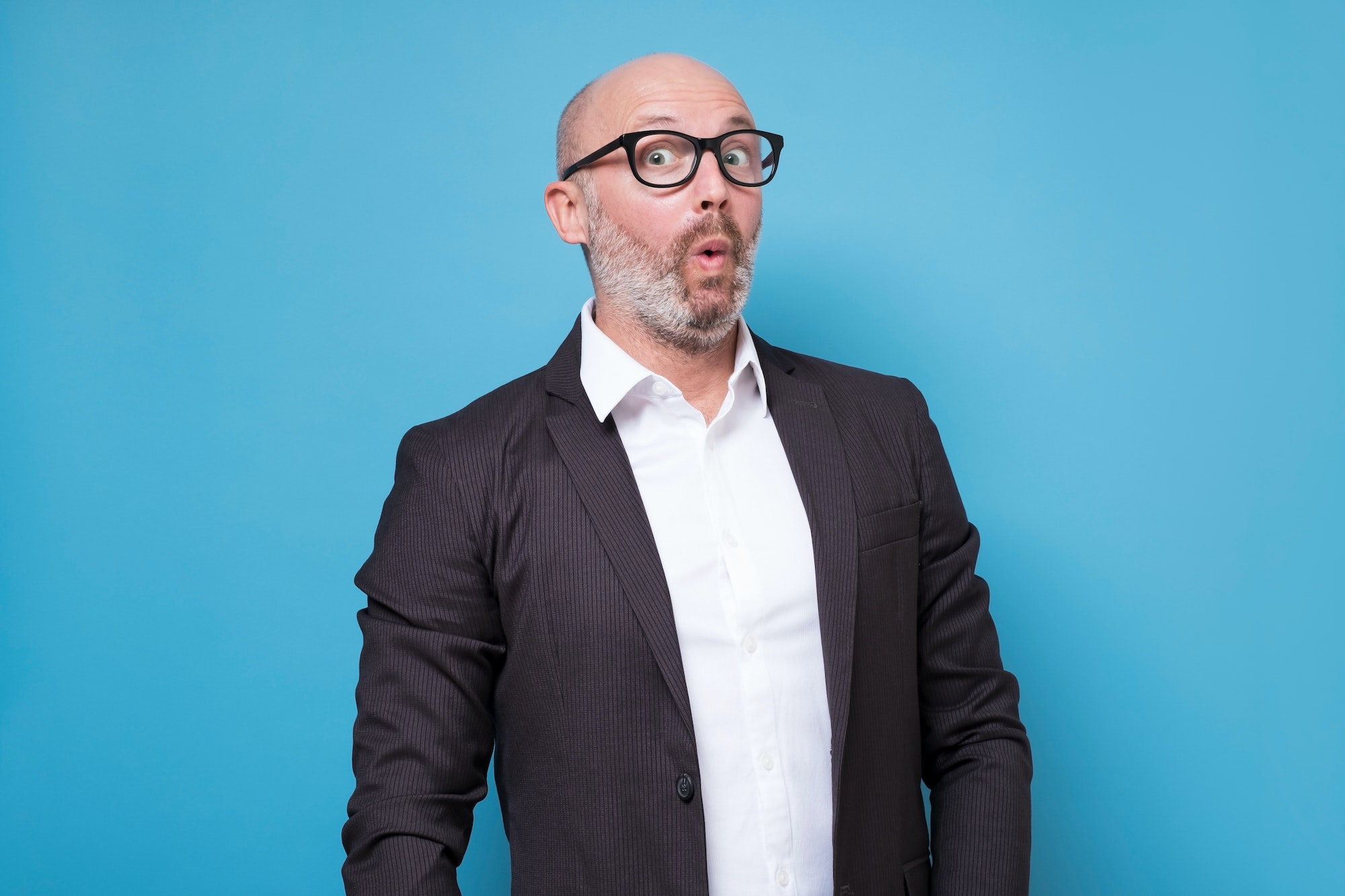 Mature hispanic man in suit with surprised face expression