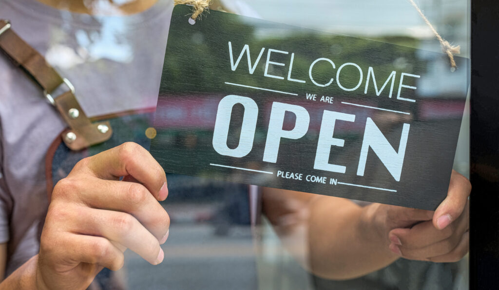 Close-up of the Business owner hand holding an open sign for service.
